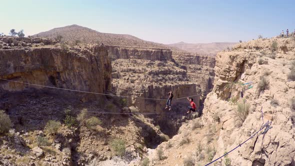 Aerial view of a man balancing while tightrope walking and slacklining across a canyon.