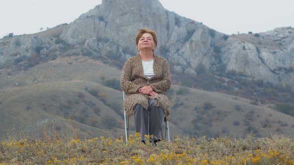 Portrait of an Elderly Woman Against the Background of an Autumn Mountain Landscape