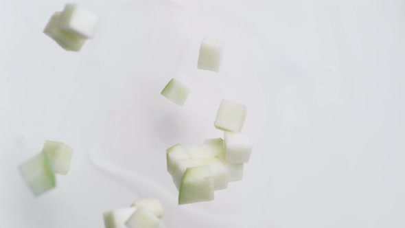 Camera follows tossing diced apple in milk. Overhead shot. Slow Motion.