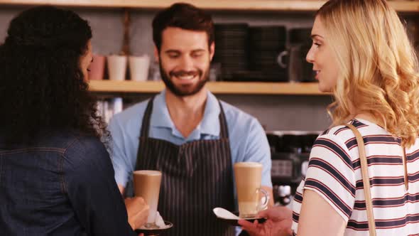 Waiter and customers having coffee at counter