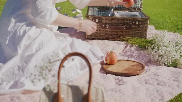 Woman Picking Fruits From Open Picnic Basket Placing on Wooden Plate at Summer