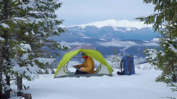 Tourist in a Tent in a Winter Forest