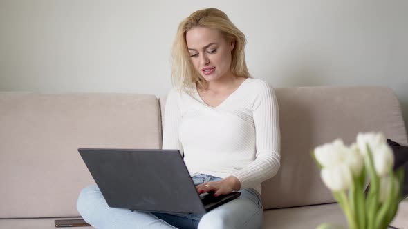 Glad Female Using Laptop on Sofa