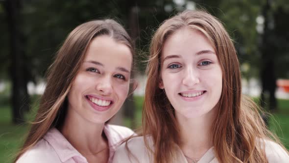 Pretty smiling girls students look at camera and smiling. Close up portrait of happy sisters.