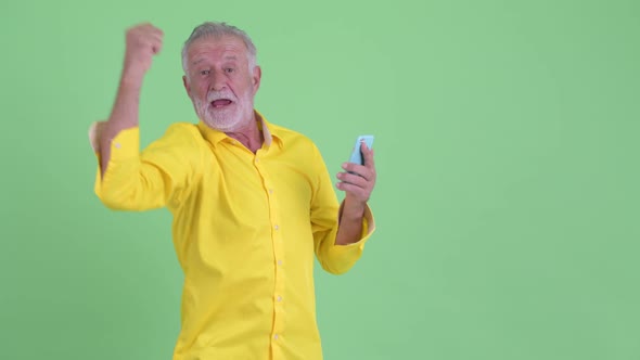 Happy Senior Bearded Businessman Using Phone and Getting Good News