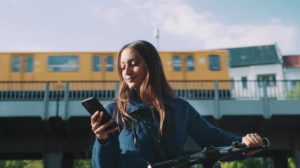 Young woman looking at her phone holding her bike