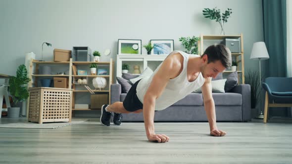 Muscular Dark-haired Guy Doing Pushup Working Out at Home in Comfortable Clothes