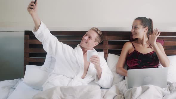 Happy Young Family Makes Selfie Resting in Bed in Morning