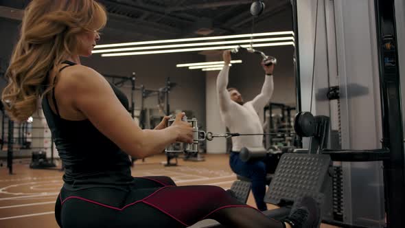 Couple in Good Physical Shape are Doing Exercises on a Exercise Machine