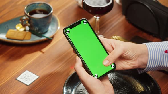 Woman Using Smartphone with Chroma Green Screen Online Menu in Cafe