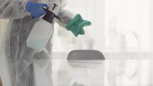 Unrecognizable Woman in Protective Suit Sanitizing Surface