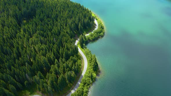 Aerial view of car driving through the fores and the lake on the side. Beautiful mountain road. 