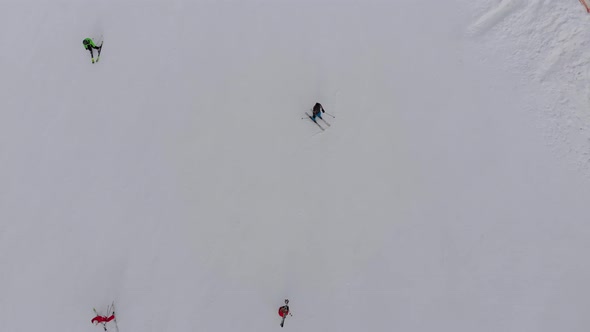 Aerial Top View of Skiers Go Down the Ski Slope on Ski Resort in Mountains