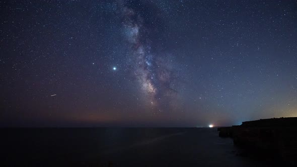 Тime lapse with Milky Way galaxy and plane trails at a rocky coastline