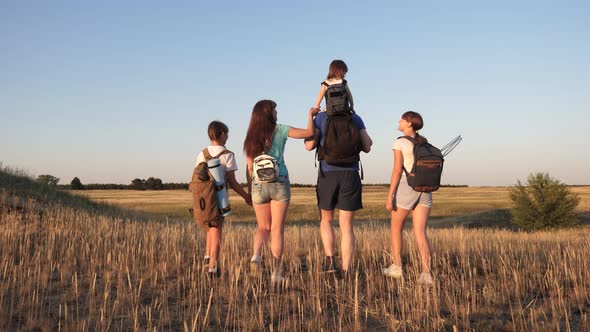 Children and Father and Mother with Backpacks Travel Through the Valley. Dad Mom with Daughters Go