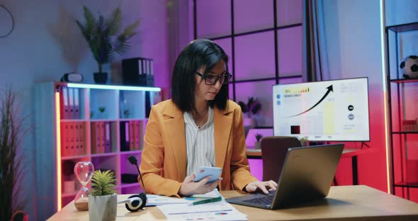 Business Lady in Glasses and Stylish Wear Working on Laptop and Then Uses Her Smartphone