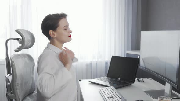 Young Businesswoman Stretching Her Back While Working on a Computer