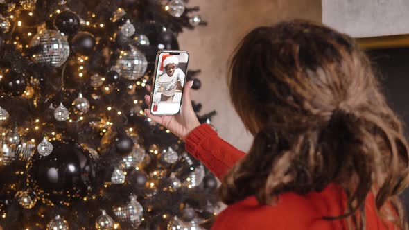 Young Woman Talks with Boyfriend Against Christmas Tree