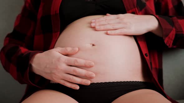 Slow motion shot of pregnant woman stroking baby belly with hands