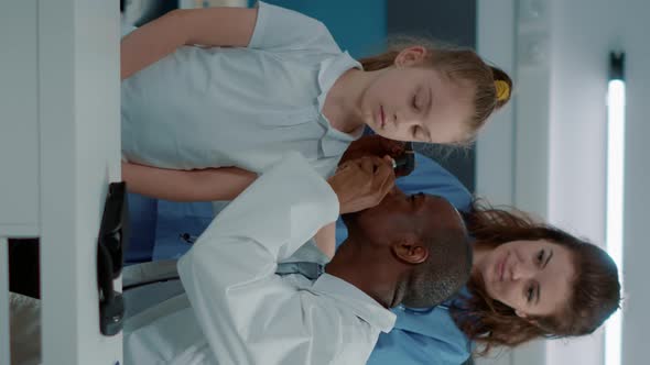 Vertical Video Physician Using Otoscope on Small Child to Do Ear Examination