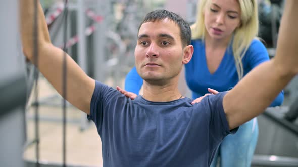 client of a gym diligently performs a row of the upper block on machine