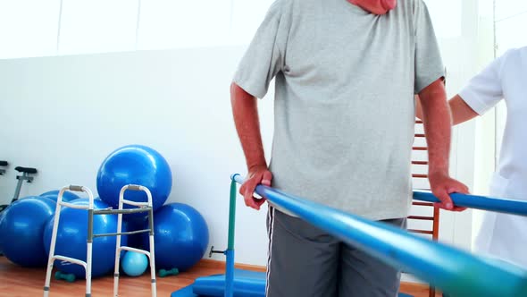 Smiling Physiotherapist Helping Patient Walk with Parallel Bars