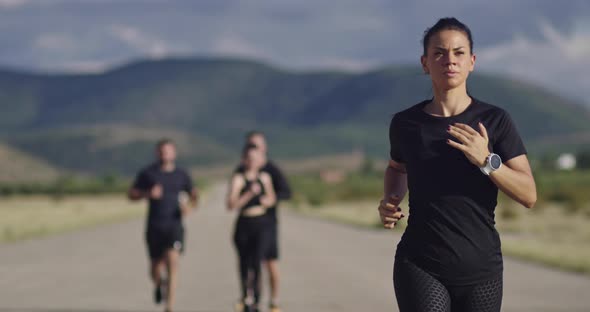 Multiethnic Group of Athletes Running Together on a Panoramic Countryside Road