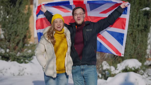 Medium Shot of Happy Couple Posing with British Flag Outdoors on Sunny Winter Day