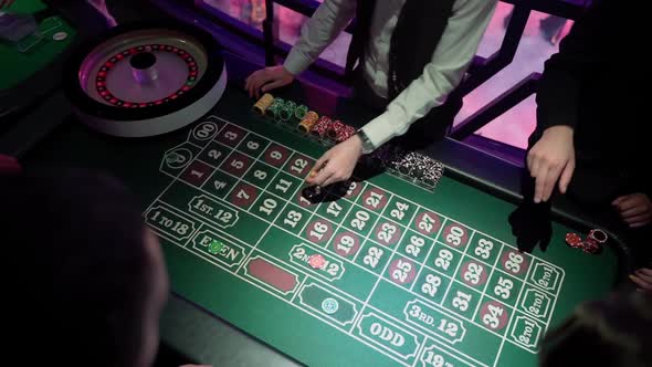 People play casino in the club. Gambling table with players hands in dark indoors
