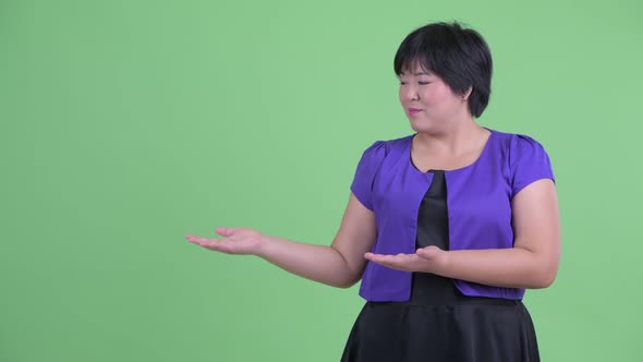 Happy Young Overweight Asian Woman Showing Something