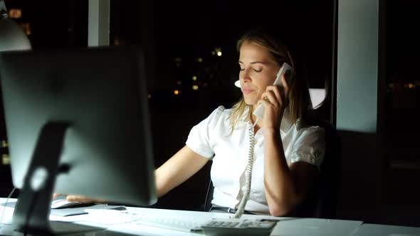 Businesswoman working over computer while talking on the phone