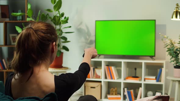 Woman Watching TV with Green Screen in Living Room Back View