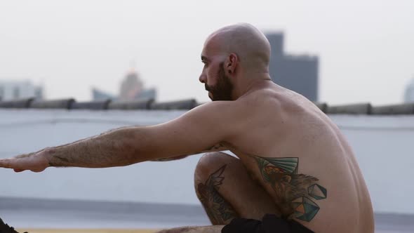 Tattooed Guy Balancing One Foot Sitting While His Hands Placed Forward