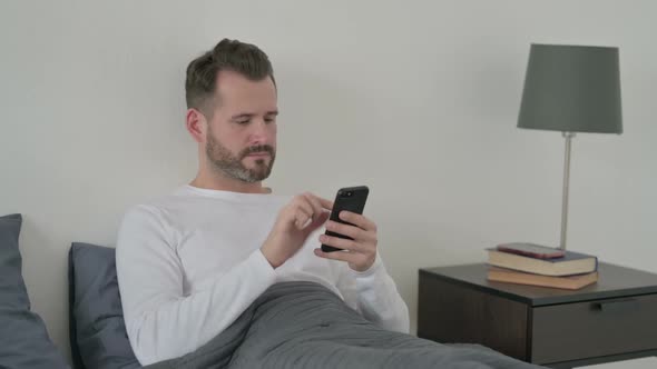 Man Using Smartphone in Bed