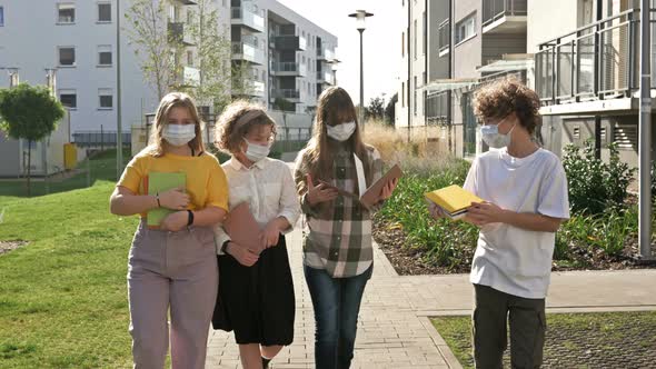 Four Teenage Schoolchildren in Medical Masks and with Books in Their Hands. Academic Year Amid the