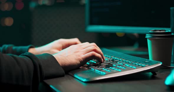 Close Up of a Young Male Hackers Hands Writing Malware on a Computer Keyboard in