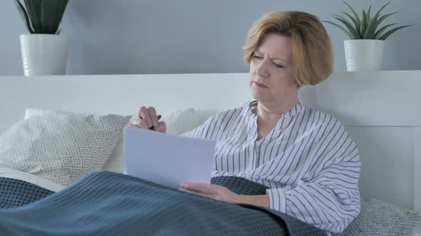 Old Senior Woman Signing Documents in Bed Paperwork