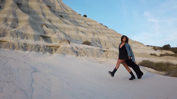 Girl with long dress walk at a desert rock. 