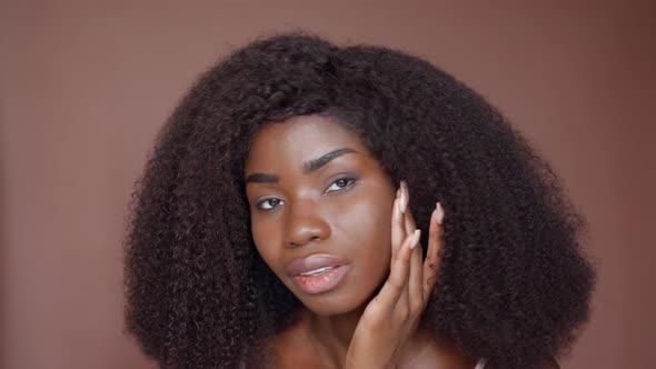 Young Black Beauty Woman Touching Face Isolated on Brown