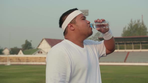 Overweight Man Drink Water At Stadium