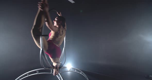 Split in a Steel Spinning Hoop By a Young Brunette Woman in Red Costume