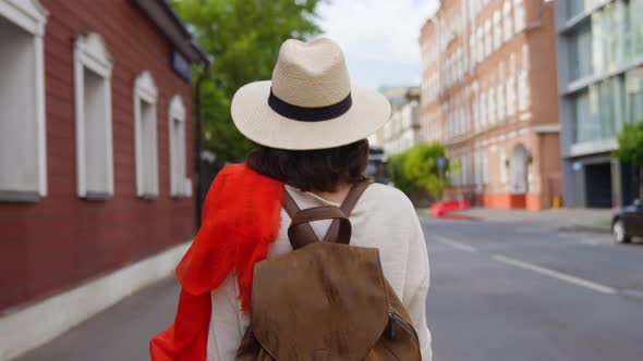 Young girl with a backpack walking down the street in the city in summer