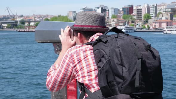 Young Man Tourist Looking Through Big Street Binoculars Telescope at Beautiful Touristic Places