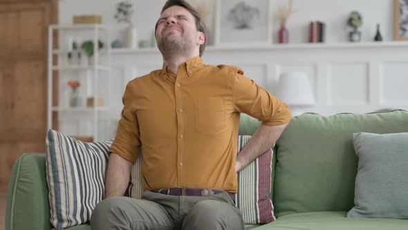 Young Man having Back Pain on Sofa