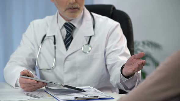 Plastic Surgeon Talking to Female Patient, Counting Surgery Costs on Tablet