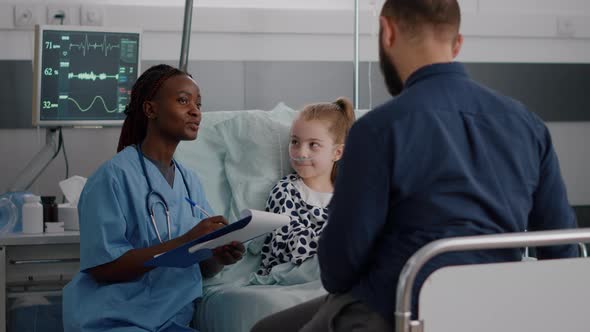 African American Pediatrician Nurse Writing Healthcare Treatment During Recovery Examination