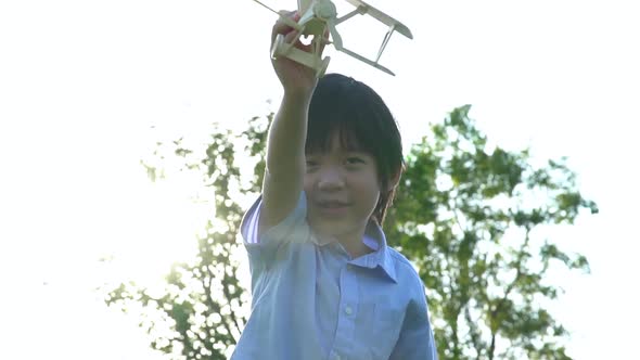 Cute Asian Child Playing Wooden Toy Plane In The Park