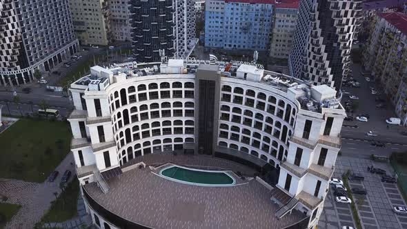 Flying over modern Batumi building looks like a coliseum and skyscrapers, Georgia. Tennis court and