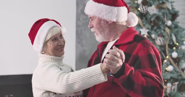 Close-up of Mature Caucasian Man with White Beard Dancing with Wife on New Year's Eve at Home