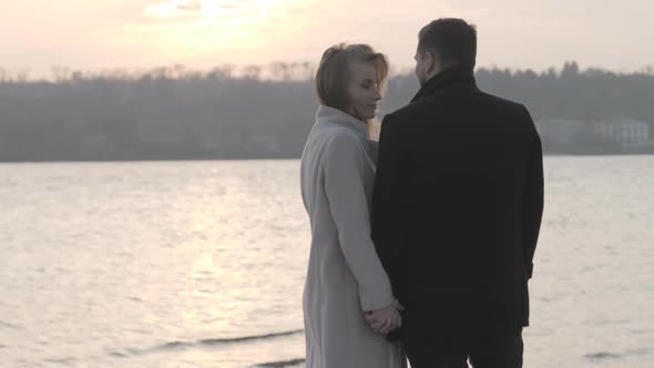 Lovers Stand By the Shore Holding Hands, at Sunset, Hugs